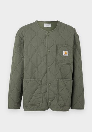Πράσινο χακί μπουφάν με καπιτονέ ραφή, κουμπιά τύπου σναπ, στρογγυλή λαιμόκοψη, τρεις εξωτερικές τσέπες και μικρό λογότυπο Carhartt στην τσέπη στο στήθος.