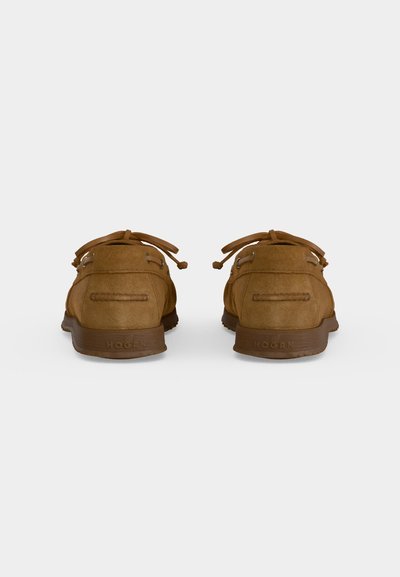 Paire de mocassins en daim marron vus de dos avec des lacets en cuir noués en petits nœuds et des semelles en caoutchouc.