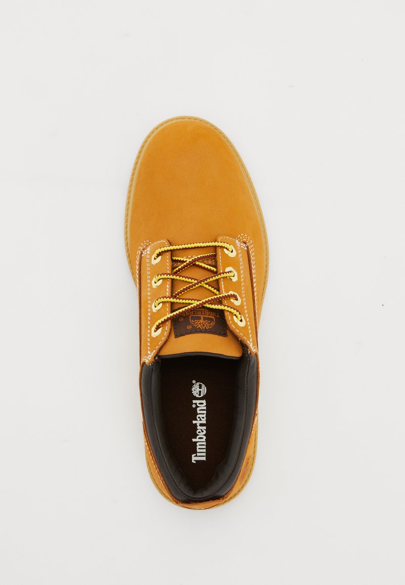 Brown suede lace-up shoe with yellow laces, rounded toe, and a padded interior. Features a brown leather lining and Timberland logo on the insole.