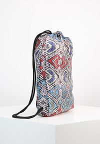 Reppurella kassi sisältää kuvioitua tekstiiliä punaisena, sinisenä ja valkoisena mustilla kahvoilla; suorakulmainen muoto pehmeällä pinnalla.