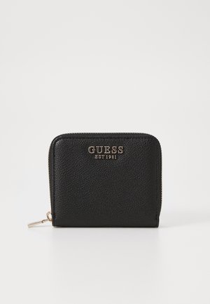 Portafoglio in pelle nera con superficie testurizzata, logo dorato del brand "GUESS EST 1981," chiusura con zip e dettagli in metallo.