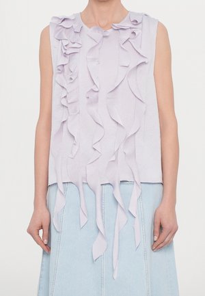 Ærmeløs lyse lavendel top med vertikale, vandfaldsagtige stofvolanter båret med lyseblåt denimskørt.