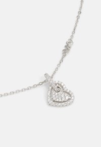 Colier din argint cu un pandantiv în formă de inimă, prezentând un buchet de pietre clare, detalii complexe și un lanț interconectat.