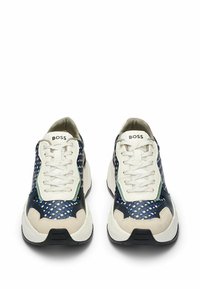 Sneakers featuring a mix of navy blue and cream materials, textured mesh panels, prominent laces, and a bold white and black sole.