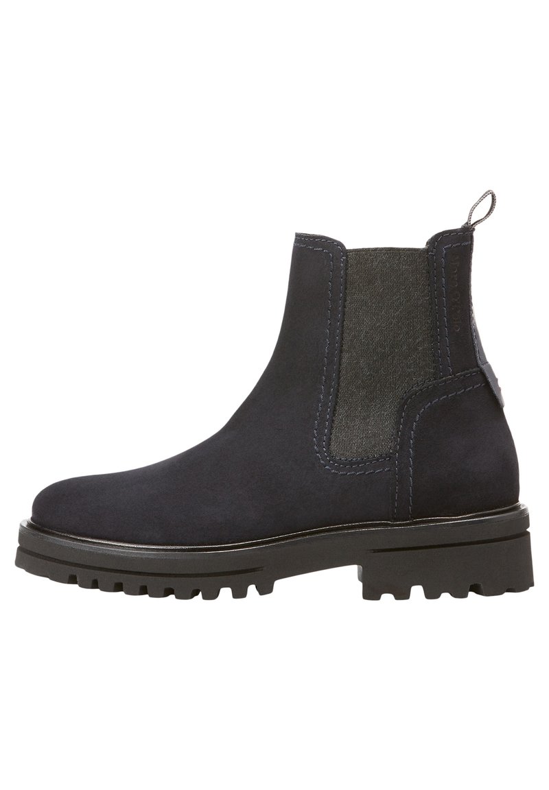 Bottines en daim bleu marine foncé avec panneaux élastiques sur les côtés, un dos texturé et une semelle en caoutchouc noir robuste. Présente des accents cousus et une poignée pour le tirage.