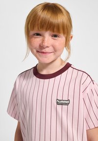 Ljusrosa t-shirt med kort ärm och mörkröda vertikala ränder samt rund halsringning. Har en svart "hummel"-logotyp på framsidan.