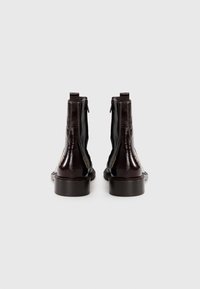 Bottes chelsea en cuir marron avec une finition brillante, dotées de fermetures éclair sur les côtés, d'accents cousus et d'une semelle épaisse.