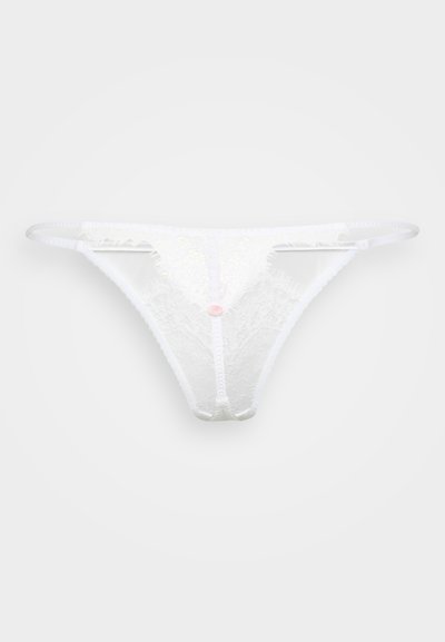 Thong en dentelle blanche présentant un motif floral, avec des sangles latérales fines et un petit bouton décoratif rose au centre. Texture de tissu transparent.