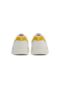 White sneakers featuring a textured leather upper, yellow heel accents, and a contrasting gray design. Flat laces and rubber sole.