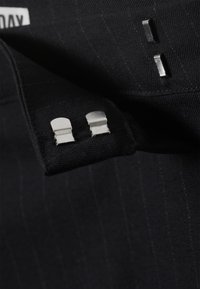 Musta kangas, jossa on hienovaraiset suorat raidat, sisältää hopeiset metallisoljet reunoilla. Tekstuuri on sileä ja rakenteellinen muotoilu.