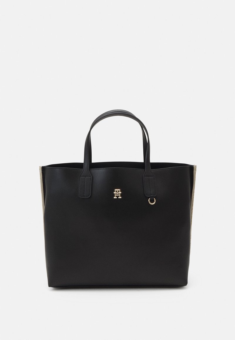 Borsa a tote in pelle nera con hardware logo dorato, manici piatti e un'accents in tessuto testurizzato sui lati. Forma rettangolare con apertura superiore.