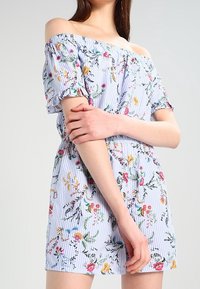 Šaty s květinovým vzorem bez ramínek, modro-bílé pruhované, s krátkými rukávy, přiléhavým pasem a živými květinovými motivy.