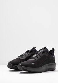 Le sneakers atletiche nere presentano una superficie texturizzata, una tomaia in rete, punta rotonda, colletto imbottito e un'unità d'aria visibile nella suola per un'ammortizzazione ottimale.