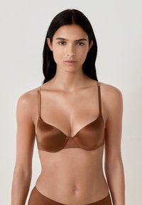 Sujetador acolchado marrón con tirantes ajustables, textura de satén suave y un diseño sin costuras, que presenta un sutil detalle de costura central.