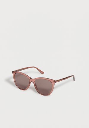 Braune durchsichtige Katzenaugen-Sonnenbrille mit dunklen Gläsern, die auf einer weißen Oberfläche liegt.