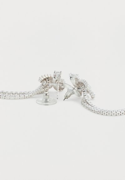 Ασημένια σκουλαρίκια με σπειροειδές σχέδιο και αλυσίδα συνδεδεμένη μεταξύ τους, με λαμπερή μεταλλική υφή και διαφανές πίσω μέρος για ασφαλή φορέματα.