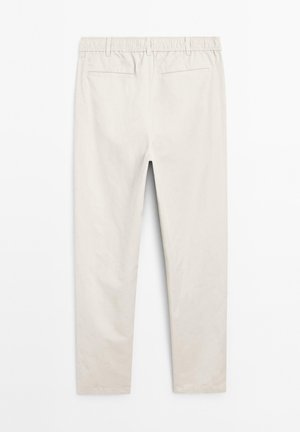 Light beige tapered pants with an elastic waistband, featuring two back pockets and a smooth, matte texture.