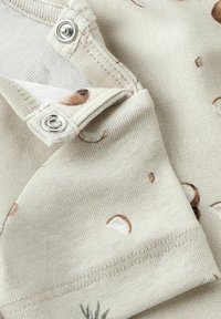 Beżowa bawełniana tkanina z zapięciem na zatrzask, ozdobiona subtelnym brązowym wzorem abstrakcyjnych kształtów i plamek. Miękka, teksturowana powierzchnia.