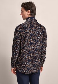 Navy Hemd mit floralem Muster in Beige und Creme. Lange Ärmel, knöpfbare Manschetten und ein Kragen. Baumwollmischgewebe mit weicher Textur.