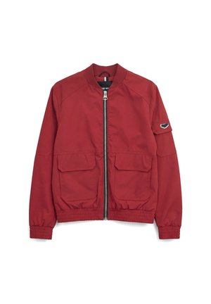 Giacca bomber rossa con cerniera frontale, due grandi tasche con patta, polsini ed orlo elasticizzati, e una piccola toppa sulla manica sinistra.