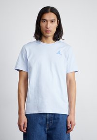 Lyseblå bomulds T-shirt med rund hals, korte ærmer og et lille blåt Jordan-logo på venstre bryst. Bæres sammen med denimshorts.