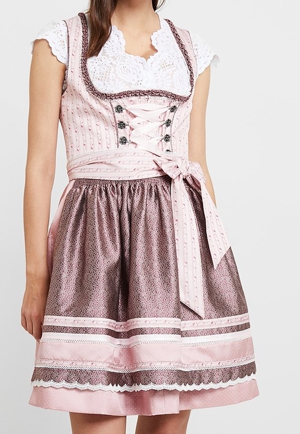 Femme portant une robe traditionnelle dirndl rose et marron avec un chemisier en dentelle, des lacets décoratifs au corsage et un tablier noué en nœud à la taille.
