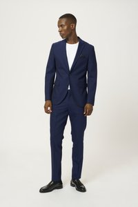 Conjunto de dos piezas en color navy con corte slim que incluye un blazer de un solo botón, solapas de muesca y pantalones a juego. Camiseta blanca en la parte inferior.