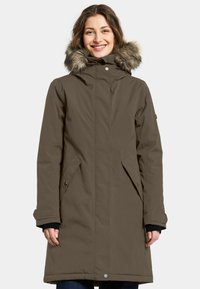 Brun vandtæt parka med hætte foret med pels, frontlynlås, sidelommer og knapdetaljer. Tekstureret stof, knælangt design.