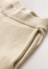 Beežid dressipüksid soonikkoes vöökohaga ja pehme tekstuuriga. Materjal on veidi tekstuuriga ja ühtlaselt siledapinnaline.