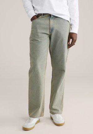 Lichtblauwe denim jeans met een relaxte pasvorm, rechtlopende pijpen, zichtbare naden en zakken, gecombineerd met witte sneakers.