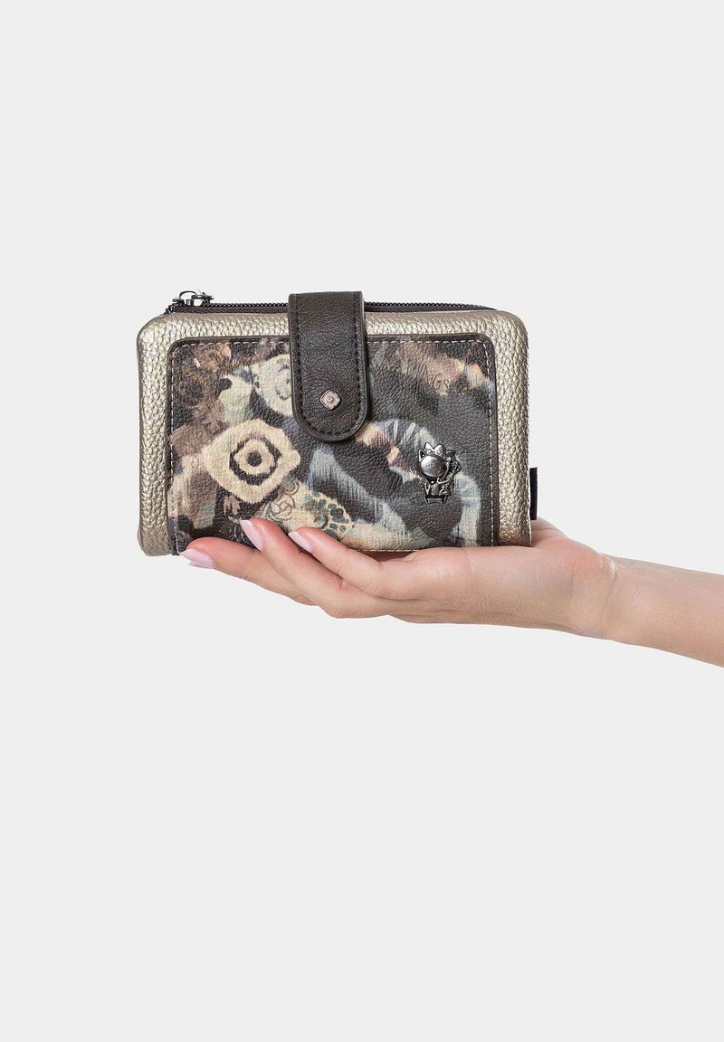 Billetera compacta con un exterior estampado en tonos terrenales, acentos en plata y un cierre de broche de cuero oscuro. Detalles de tela texturizada y hardware.