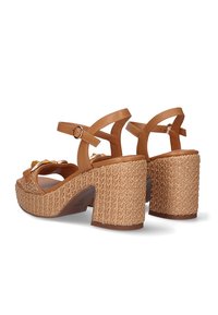 Sandalias de plataforma marrones con amplios tacones trenzados, correas ajustables en el tobillo y adornos decorativos en la parte superior. Superficie texturizada, diseño casual.