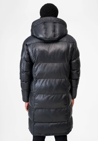 Schwarzer Steppmantel mit gesteppter Optik, hohem Kragen und Kapuze. Hergestellt aus glänzendem Stoff mit leicht oversized Passform.