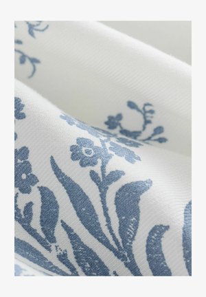 Tessuto bianco con un motivo intrecciato testurizzato che presenta disegni floreali e fogliari blu. Gli accenti blu contrastano con lo sfondo bianco.
