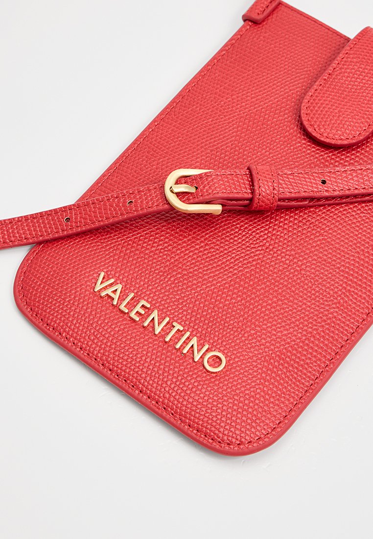 Pochete de couro texturizado vermelho da Valentino com uma alça fina que apresenta uma pequena fivela dourada, exibida sobre uma superfície branca.