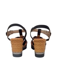 Sandali neri con tacco, dotati di cinturini intrecciati in tono testa di moro e un tacco testurizzato simile al sughero, caratterizzati da un piccolo dettaglio in argento alla base.