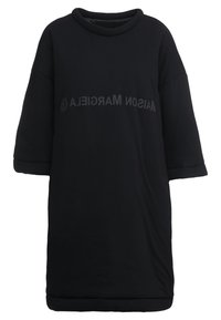 Czarna, oversize sukienka z miękkiej tkaniny, z okrągłym dekoltem i krótkimi rękawami. Na piersi wyraźny napis "MAISON MARGIELA".