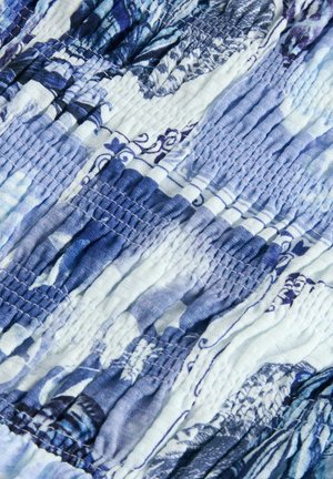 Textúrált anyag kék és fehér árnyalatokban, begyűrt részekkel, absztrakt virágmintákkal és puha, nyújtható anyaggal.