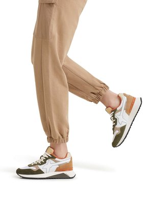 Zapatillas con cordones que presentan una combinación de colores blanco, olivo y óxido, con una parte superior de ante y malla, suela acolchada y suela texturizada.
