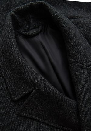 Donkergrijze wollen jas met een gestructureerde buitenkant, een ingezette kraag en een soepele zwarte binnenvoering. Close-up van de kraag en stof.