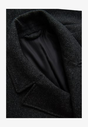 Donkergrijze wollen jas met een gestructureerde buitenkant, een ingezette kraag en een soepele zwarte binnenvoering. Close-up van de kraag en stof.