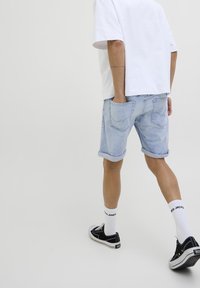 Shorts in denim blu chiaro con risvolti, vestibilità comoda e tasche posteriori. Abbinati a una t-shirt bianca e sneakers nere.