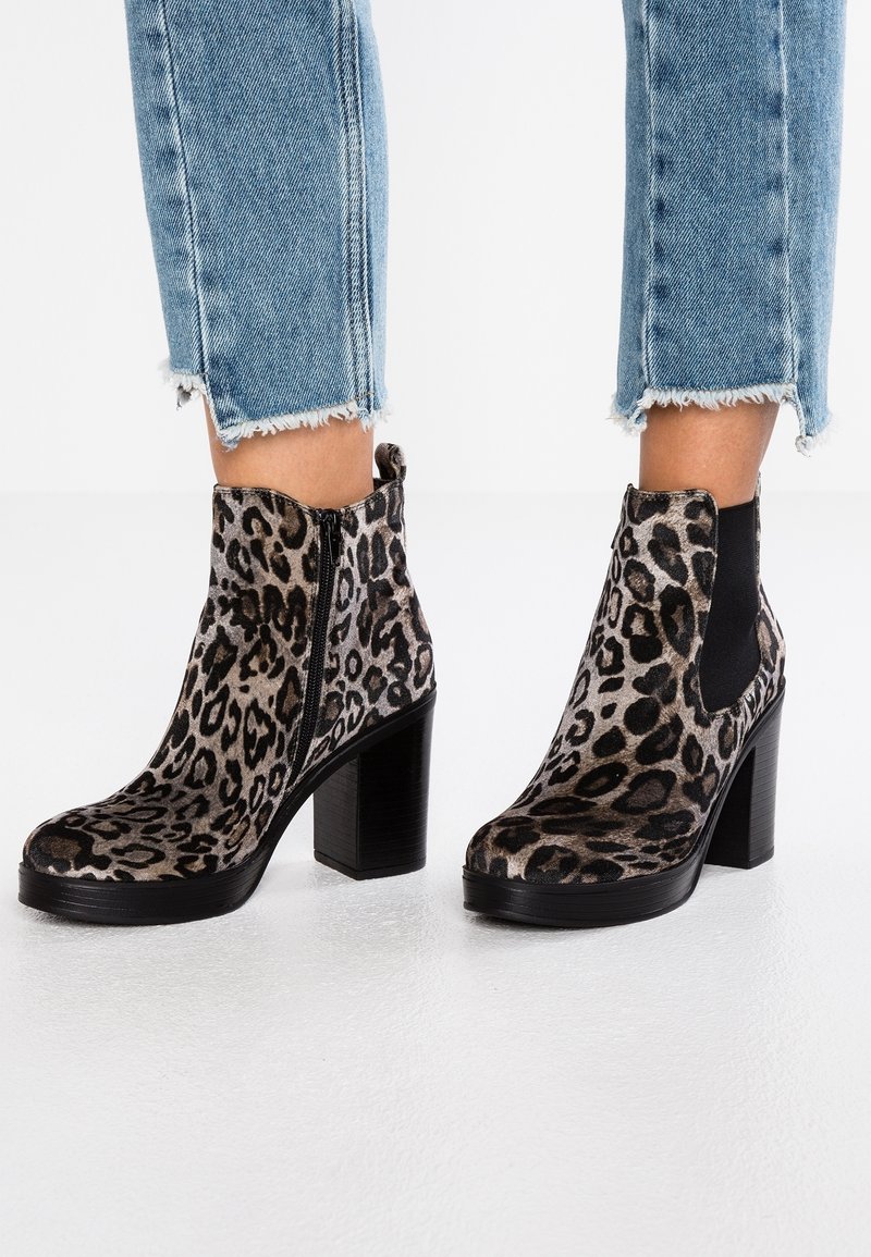 Bottes montantes à imprimé léopard avec talons épais, portées avec un jean bleu clair court aux ourlets effilochés.