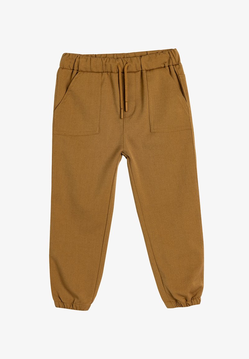 Brune, strækbare stofbukser med elastisk talje, snøre og to forreste lommer. Taperede ben med elastiske manchetter ved anklerne.