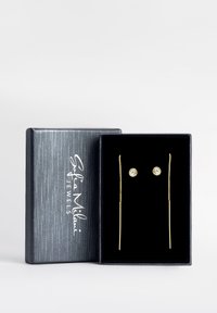 Orecchini d'oro in una scatola foderata in velluto nero, con design a bottone circolare e a bastoncino allungato, arricchiti da accenti di pietre scintillanti.