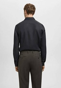 Zwart overhemd met lange mouwen, een klassieke kraag, geruite manchetten en een gladde stof, gecombineerd met donkergroene broek met achterzakken.