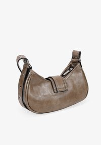 Bolso de hombro de cuero marrón con forma curvada, que cuenta con una correa cosida y acentos de metal, bolsillo con cremallera en un lado.