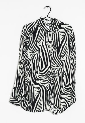 Czarna i biała bluzka w wzór zebry z długimi rękawami, kołnierzykiem oraz lekko zaokrąglonym dołem, wykonana z lekkiego, teksturowanego materiału.