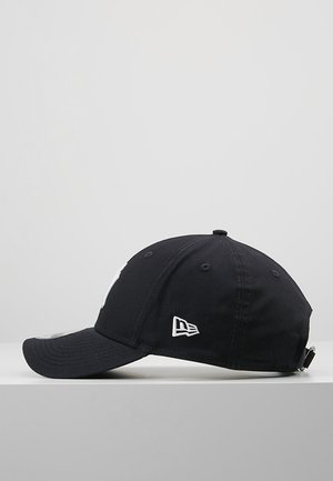 Cappellino da baseball nero con visiera curva e piccolo logo bianco sul lato, esposto su una superficie grigia su sfondo grigio chiaro.