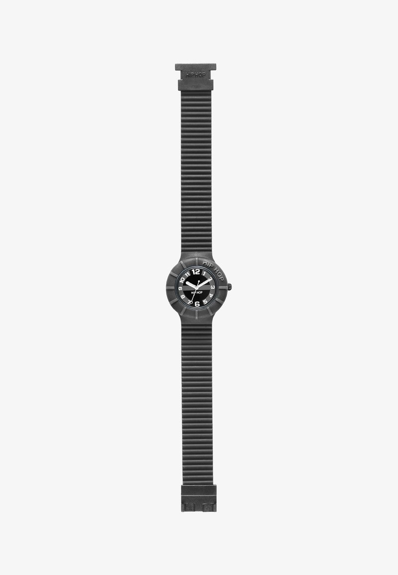 Reloj de goma negra con cara redonda, marcadores de hora blancos y correa estriada. Las características incluyen un logo prominente y un diseño de esfera simple.